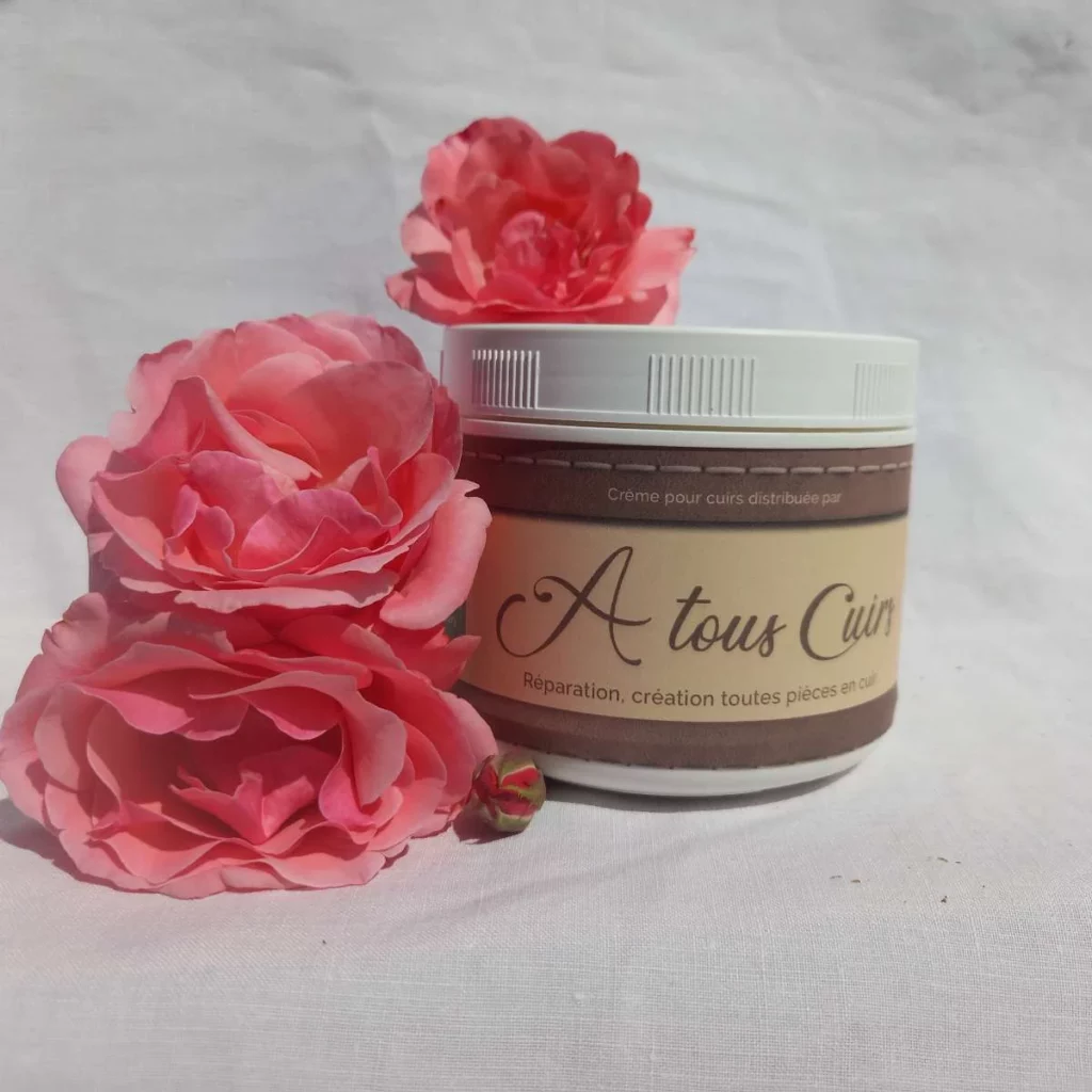 Pot de crème cuir A Tous Cuirs entouré de roses roses, élégance naturelle en Gironde,