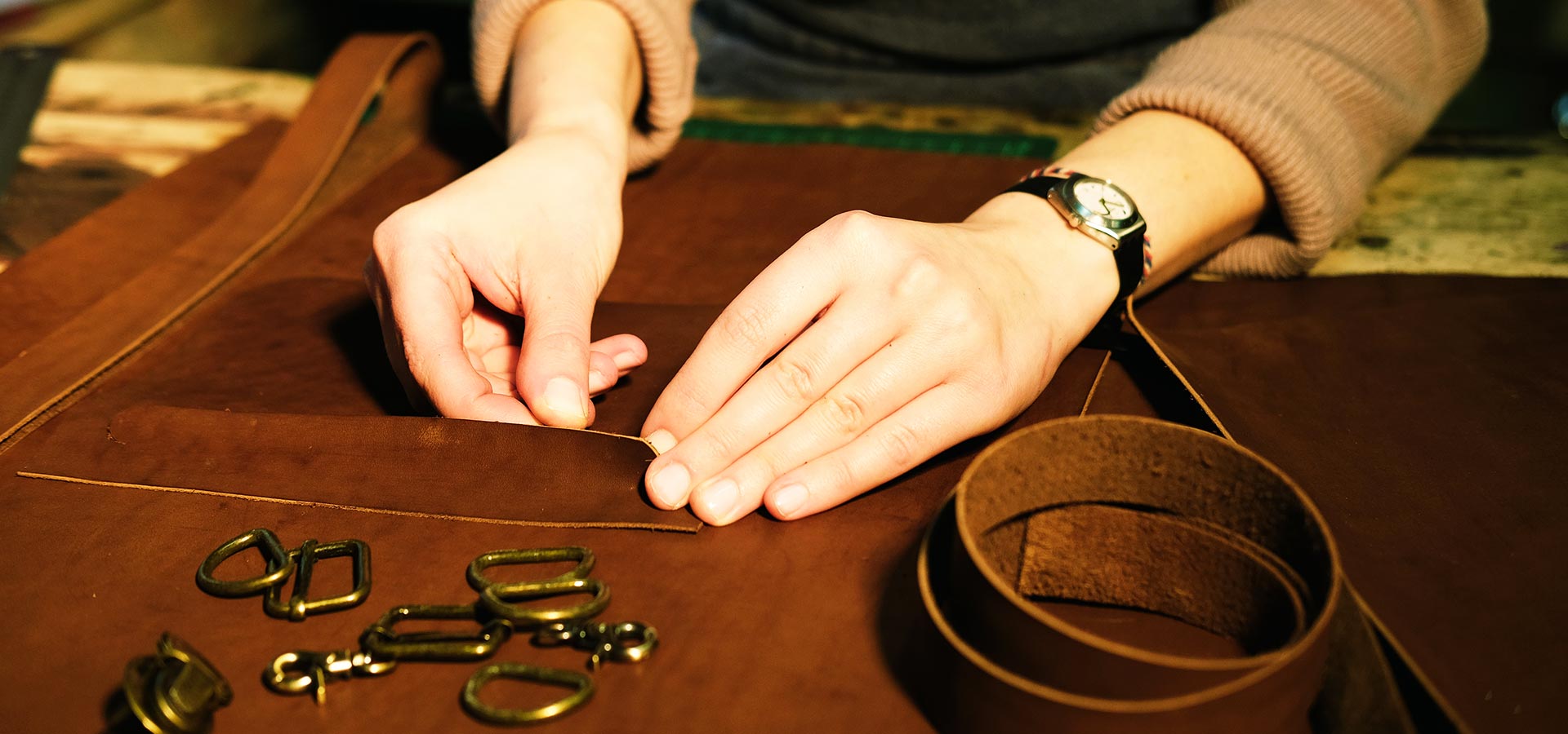 atelier cuir A Tous Cuirs en Gironde, création artisanale d’accessoires en cuir avec outils et mains au travail,